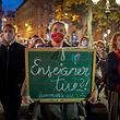 PARIS, FRANCE - OCTOBER 21: A member of the crowd watching the National Tribute to the murdered school teacher Samuel Paty holds a teachers chalk board reading 'Teaching Kills?!' at Place de la Sorbonne on October 21, 2020 in Paris, France. 401 official guests, including 100 school children, attended the national tribute to slain teacher Samuel Paty at the historical seat of French pedagogy la Sorbonne university grounds. Crowds gathered to watch the ceremony on giant screens nearby. Samuel Paty was assassinated for showing caricatures of Mohammed in a civics class on freedom of speech at College Bois d'Aulne in a Parisian suburb on October 16. (Photo by Kiran Ridley/Getty Images)