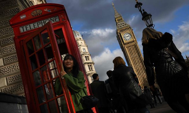 A tourist poses for a photograph inside a red telephone box in central London on January 31, 2023
