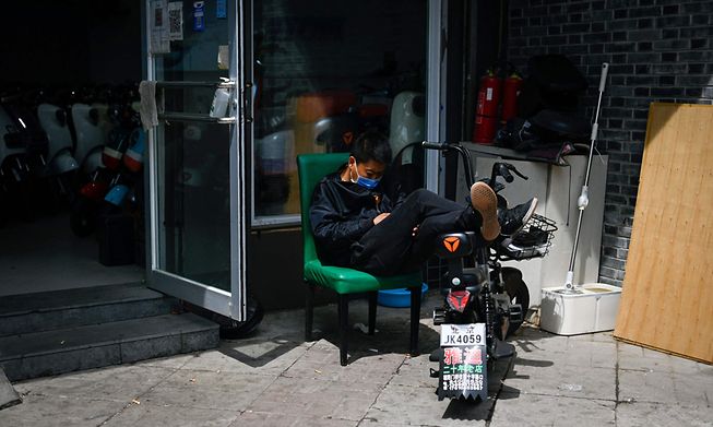 A salesman waits for customers at the entrance of a electric bicycle shop in Beijing on Thursday