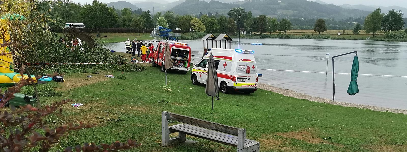 Rettungsfahrzeuge stehen neben umgekippten Bäumen an einer Unfallstelle am St. Andräer See.