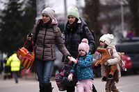 Ukrainian evacuees walk at the Ukrainian-Romanian border in Siret, northern Romania, on March 16, 2022. - More than three million people have fled Ukraine since the start of the invasion, the UN migration agency IOM says. Around half are minors, says the UN children's agency. (Photo by Armend NIMANI / AFP)