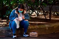 A woman wearing a face mask checks a package delivered by Amazon on March 19, 2020 in Rome, during the country's lockdown aimed at stopping the spread of the COVID-19 (new coronavirus) pandemic. - Italy braced on March 19, 2020 for an extended lockdown that could see the economy suffer its biggest shock since World War II from a pandemic that has killed almost as many people as it has in China. (Photo by Laurent EMMANUEL / AFP)