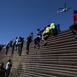 TOPSHOT - A group of Central American migrants -mostly Hondurans- climb a metal barrier on the Mexico-US border near El Chaparral border crossing, in Tijuana, Baja California State, Mexico, on November 25, 2018. - US officials closed the San Ysidro crossing point in southern California on Sunday after hundreds of migrants, part of the "caravan" condemned by President Donald Trump, tried to breach a fence from Tijuana, authorities announced. (Photo by Pedro PARDO / AFP)