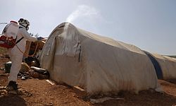 TOPSHOT - A member of the Syrian Civil Defence, also known as the "White Helmets", disinfects a tent in the Kafr Lusin camp for the displaced by the border with Turkey, in Syria's rebel-held northwestern province of Idlib, on March 24, 2020, as part of efforts to prevent the spread of coronavirus. - The virus is the latest threat to the three million people who live in Idlib, many of whom are now reduced to living in camps without basic amenities in Syria's last major rebel bastion, where a fragile truce has largely halted the government's bombardment since the start of the month. (Photo by AAREF WATAD / AFP)