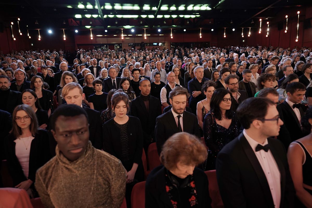 Das Publikum steht während einer Schweigeminute für die Opfer des Anschlages in Hanau bei der feierlichen Eröffnung der Internationalen Filmfestspiele.