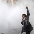 TOPSHOT - An Iranian woman raises her fist amid the smoke of tear gas at the University of Tehran during a protest driven by anger over economic problems, in the capital Tehran on December 30, 2017. Students protested in a third day of demonstrations sparked by anger over Iran's economic problems, videos on social media showed, but were outnumbered by counter-demonstrators. / AFP PHOTO / STR