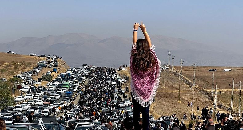 -- AFP PICTURES OF THE YEAR 2022 -- This UGC image posted on Twitter reportedly on October 26, 2022 shows an unveiled woman standing on top of a vehicle as thousands make their way towards Aichi cemetery in Saqez, Mahsa Amini's home town in the western Iranian province of Kurdistan, to mark 40 days since her death, defying heightened security measures as part of a bloody crackdown on women-led protests. - A wave of unrest has rocked Iran since 22-year-old Amini died on September 16 following her arrest by the morality police in Tehran for allegedly breaching the country's strict rules on hijab headscarves and modest clothing. (Photo by UGC / AFP) / AFP PICTURES OF THE YEAR 2022 === RESTRICTED TO EDITORIAL USE - MANDATORY CREDIT "AFP PHOTO / UGC IMAGE" - NO MARKETING NO ADVERTISING CAMPAIGNS - DISTRIBUTED AS A SERVICE TO CLIENTS FROM ALTERNATIVE SOURCES, AFP IS NOT RESPONSIBLE FOR ANY DIGITAL ALTERATIONS TO THE PICTURE'S EDITORIAL CONTENT, DATE AND LOCATION WHICH CANNOT BE INDEPENDENTLY VERIFIED === / 