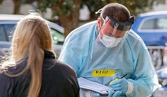 A health worker takes details at a COVID-19 testing station setup at Eden Park, National Sports Stadium, in Auckland on August 14, 2020. - New Zealand rushed to track the source of a sudden return of the coronavirus as the number of new cases in its biggest city rose to 17 and officials warned more infections were inevitable. (Photo by DAVID ROWLAND / AFP)