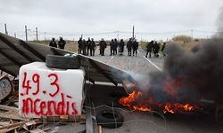 Gendarmes in riot gear stand behind a barricade with a fire as they work to secure the access to the Frontignan oil depot, blocked by protesters, a week after the government pushed a pensions reform through parliament without a vote, using the article 49.3 of the constitution, in Frontignan, southern France, on March 24, 2023. - The French president faced mounting pressure on March 24 after violent demonstrations that left more than 400 security forces injured and the centre of major cities shrouded in tear gas and smoke. More than 450 people were arrested on March 23 during the most violent day of protests since the start of the year against the president's bid to raise the retirement age from 62 to 64. (Photo by Pascal GUYOT / AFP)