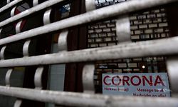 (FILES) In this file photo taken on March 11, 2021 a sign reading 'Corona - message to all...' is seen behind the closed shutter of a shop in Berlin. - Germany is poised to tighten a partial lockdown into April to halt an exponential spread of the coronavirus driven by variants. Europe's biggest economy had progressively began easing restrictions, first reopening schools in late February, before allowing some shops to resume business in March. But hopes for indoor dining, cultural and leisure facilities to follow suit will now have to be delayed, as a third wave of the virus has sent infections numbers rising again. (Photo by Tobias Schwarz / AFP)