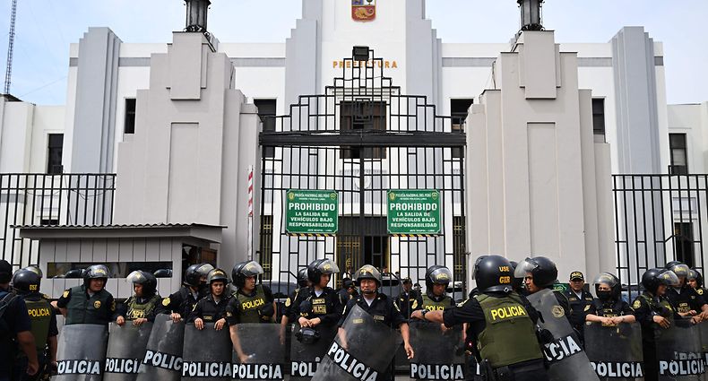 Members of the Peruvian police stand guard outside the Lima Prefecture, where Peru's President Pedro Castillo is alleged to be, in Lima, on December 7, 2022. - Peru's President Pedro Castillo dissolved Congress on December 7, 2022, announced a curfew and said he will form an emergency government that will rule by decree, just hours before the legislature was due to debate a motion of impeachment against him. (Photo by ERNESTO BENAVIDES / AFP)