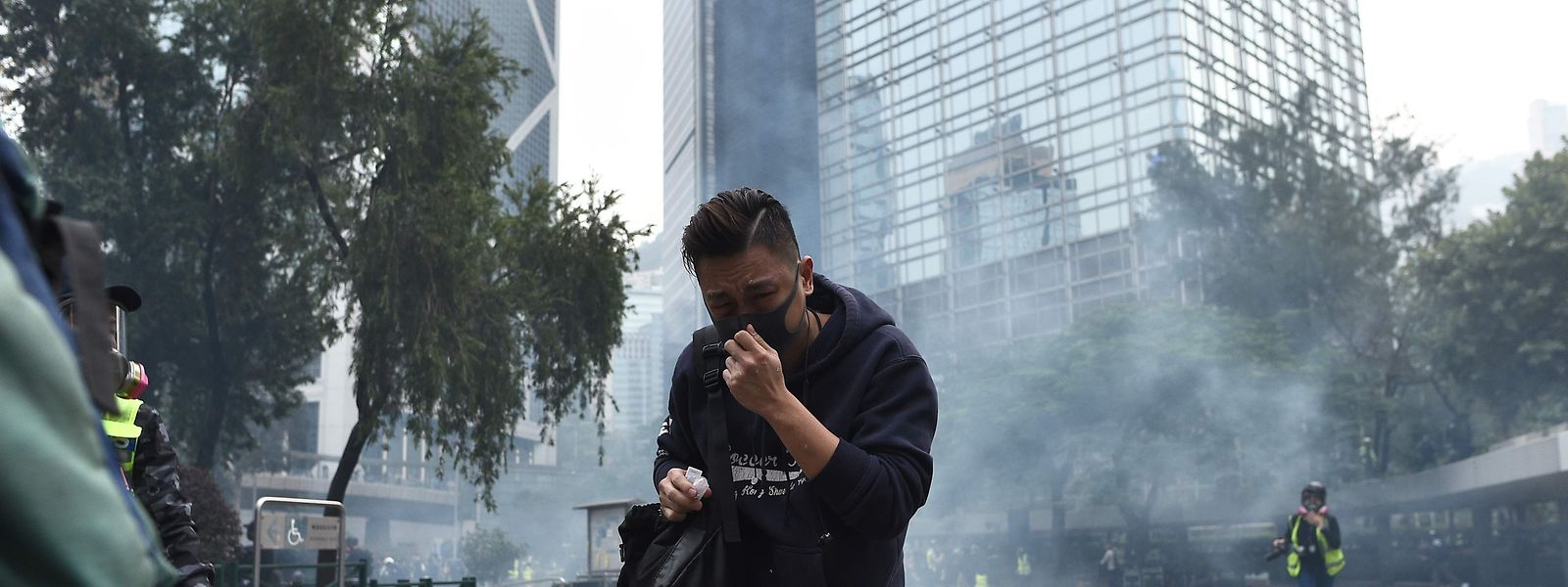People react from tear gas fired by police to disperse the crowd gathered for the 'universal siege on communists' rally at Chater Garden in Hong Kong on January 19, 2020. - Violence returned to Hong Kong's streets on January 19 with police firing tear gas to disperse crowds after a group of officers were beaten bloody by pro-democracy protesters. Thousands of people had gathered in the city's commercial district for a sanctioned rally calling for greater democratic freedoms and police accountability, the latest in seven months of protests that have upended the financial hub. (Photo by Philip FONG / AFP)