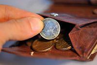 Eine Hand nimmt eine Euro-Münze aus einem Geldbeutel. 