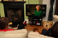 A picture shows a family in Birkenhead, northwest England on April 5, 2020 watching Britain's Queen Elizabeth II deliver a special address to the UK and  Commonwealth recorded at Windsor Castle in relation to the coronavirus outbreak. - Queen Elizabeth II urgeed people to rise to the challenge posed by the coronavirus outbreak, in a rare special address to Britain and Commonwealth nations on Sunday. (Photo by PAUL ELLIS / AFP)
