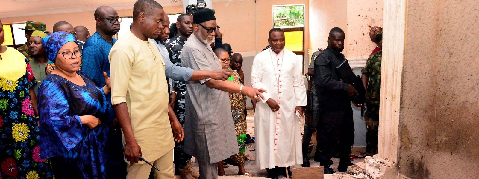 Der Gouverneur des Bundesstaates Ondo, Rotimi Akeredolu (3. v. l.), zeigt auf den blutbefleckten Boden der Kirche in der Stadt Owo im Südwesten Nigerias, wo es zu einem Blutbad kam.
