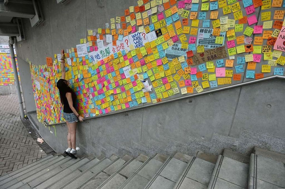TOPSHOTS A pro-democracy demonstrators places messages of support along a wall near the Hong Kong government headquarters on October 2, 2014. Hong Kong has been plunged into the worst political crisis since its 1997 handover as pro-democracy activists take over the streets following China's refusal to grant citizens full universal suffrage. AFP PHOTO / DALE DE LA REY