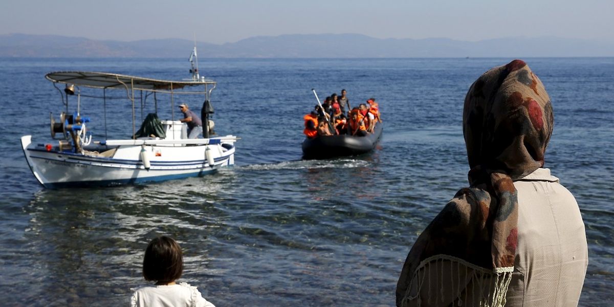 Ein griechischer Fischer zieht ein Schlauchboot mit Flüchtlingen an Land.