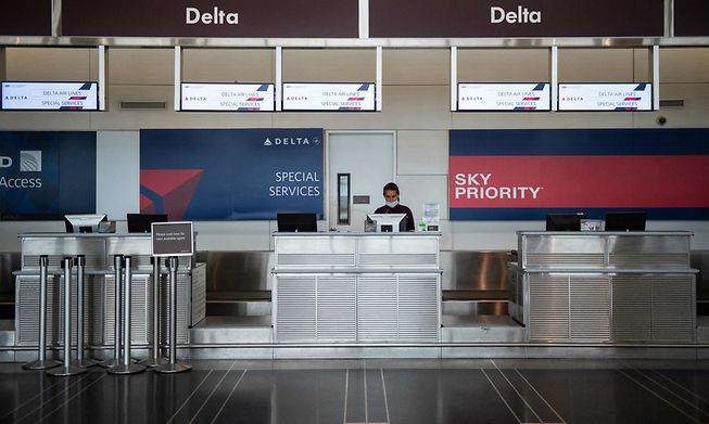 A Delta airlines employee waits for passengers at a check-in counter in Washington, DC, on 12 May, 2020.