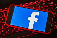 ARCHIV - 27.03.2018, München: Ein iPhone mit dem Logo von Facebook liegt auf der rot beleuchteten Tastatur eines Laptops. Soziale Medien spielen im Wahlkampf vor der Europawahl eine wichtige Rolle. (zu «Die Europawahl im Visier? Wie Roboter im Internet Meinung machen») Foto: Lino Mirgeler/dpa +++ dpa-Bildfunk +++