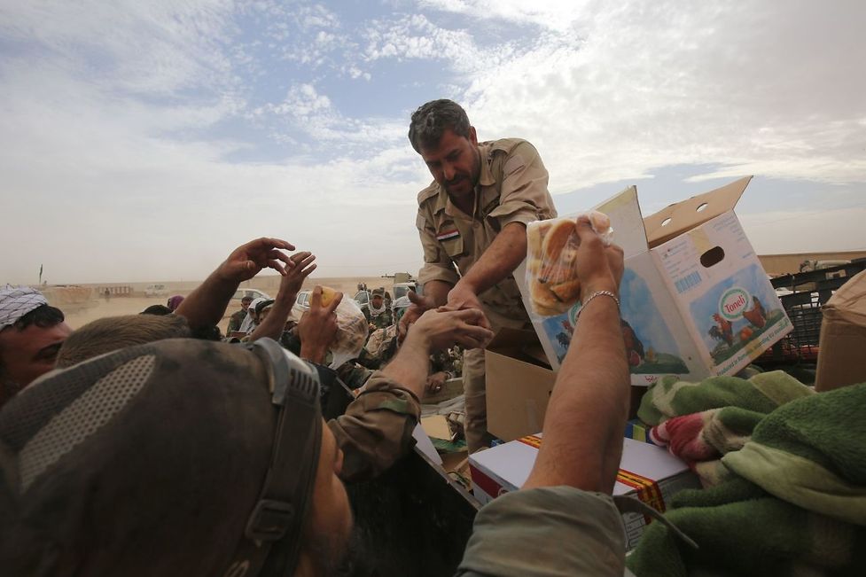 Iraqi forces distribute food as they enter the village of Abu Shuwayhah, south of jihadist-held Mosul, on November 1, 2016