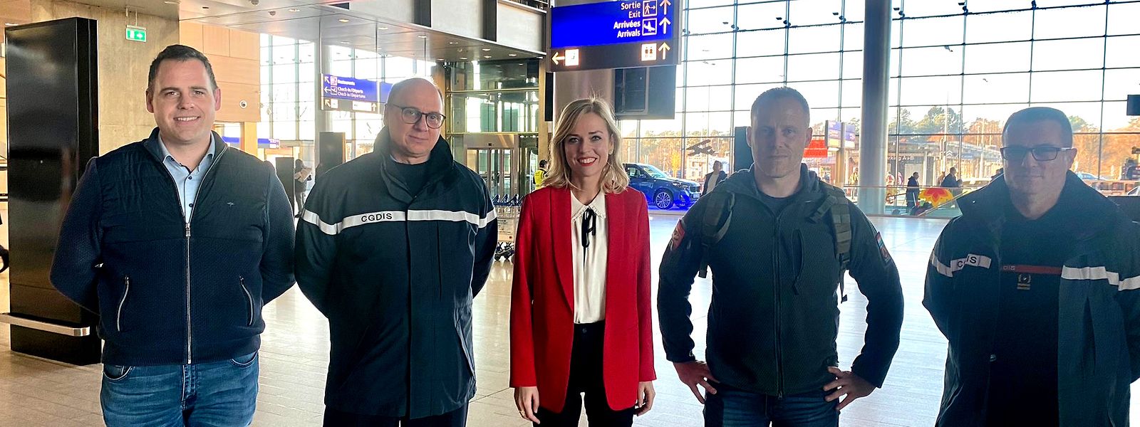 Fotografia do voluntário luxemburguês, no aeroporto, acompanhado, entre outros, pela ministra do Interior, Taina Bofferding.
