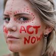 A climate activist "act now" written on her face as she joins students and youth activists outside the Houses of Parliament in London on May 24, 2019 to demand action to tackle climate change.  (Photo by Tolga Akmen / AFP)