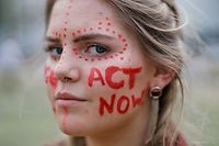 A climate activists has "Act Now" written on her face as she joins student and youth activists outside the Houses of Parliament in London on May 24, 2019 to demand action to tackle climate change. (Photo by Tolga Akmen / AFP)