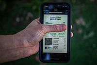 ARCHIV - 26.02.2021, Israel, Tel Aviv: Ein israelischer Mann hält ein Smartphone in der Hand, auf dem der sogenannte "Grüne Pass" abgebildet ist. In einem Versuch, aus den Corona-Maßnahmen zur Normalität zurückzukehren, hat die israelische Regierung damit begonnen, Zertifikate an Menschen auszugeben, die vollständig geimpft sind. Der "Grüne Pass" wird benötigt, um bestimmte Orte zu betreten und an bestimmten Aktivitäten teilzunehmen. (Zu dpa "Fußballfans kehren in Israels Stadien zurück - Impfung ist aber nötig") Foto: Ilia Yefimovich/dpa +++ dpa-Bildfunk +++