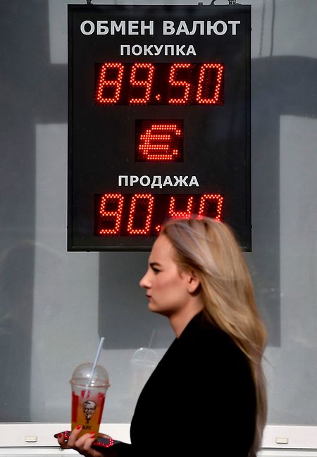 A woman walks past a screen displaying the currency exchange rate of the Russian ruble with Euro on Monday. PHOTO: AFP