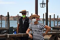 Gondoliers wearing protective face masks wait for tourists on May 30, 2020 in Venice, as the country eases its lockdown aimed at curbing the spread of the COVID-19 infection, caused by the novel coronavirus. (Photo by ANDREA PATTARO / AFP)