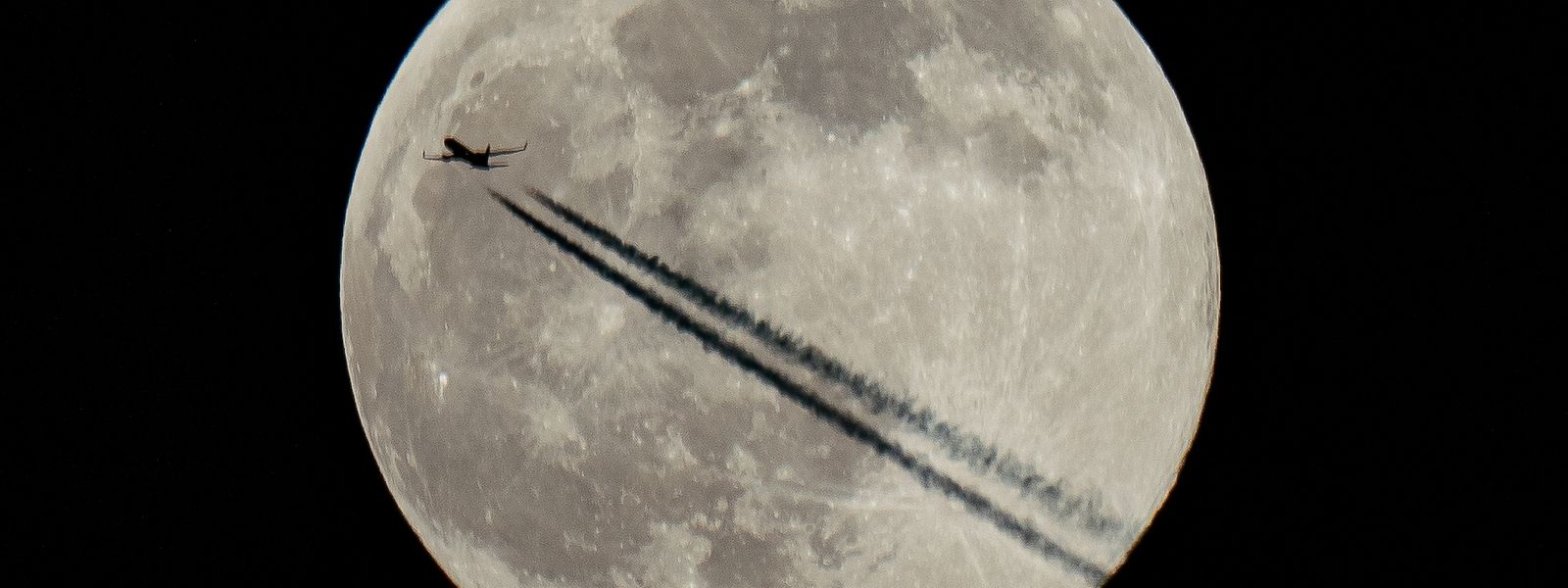 Ein Flugzeug fliegt am Mond vorbei, dem ersten Vollmond des Jahres 2022, der von nordamerikanischen Ureinwohnern als "Wolfsmond" bezeichnet wird.