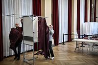 City hall employees install a voting booth in the polling place of the 10th Paris district city hall in Paris on April 8, 2022. - French voters head to the polls on April 10 and 24 for a two-round pesidential election. (Photo by STEPHANE DE SAKUTIN / AFP)